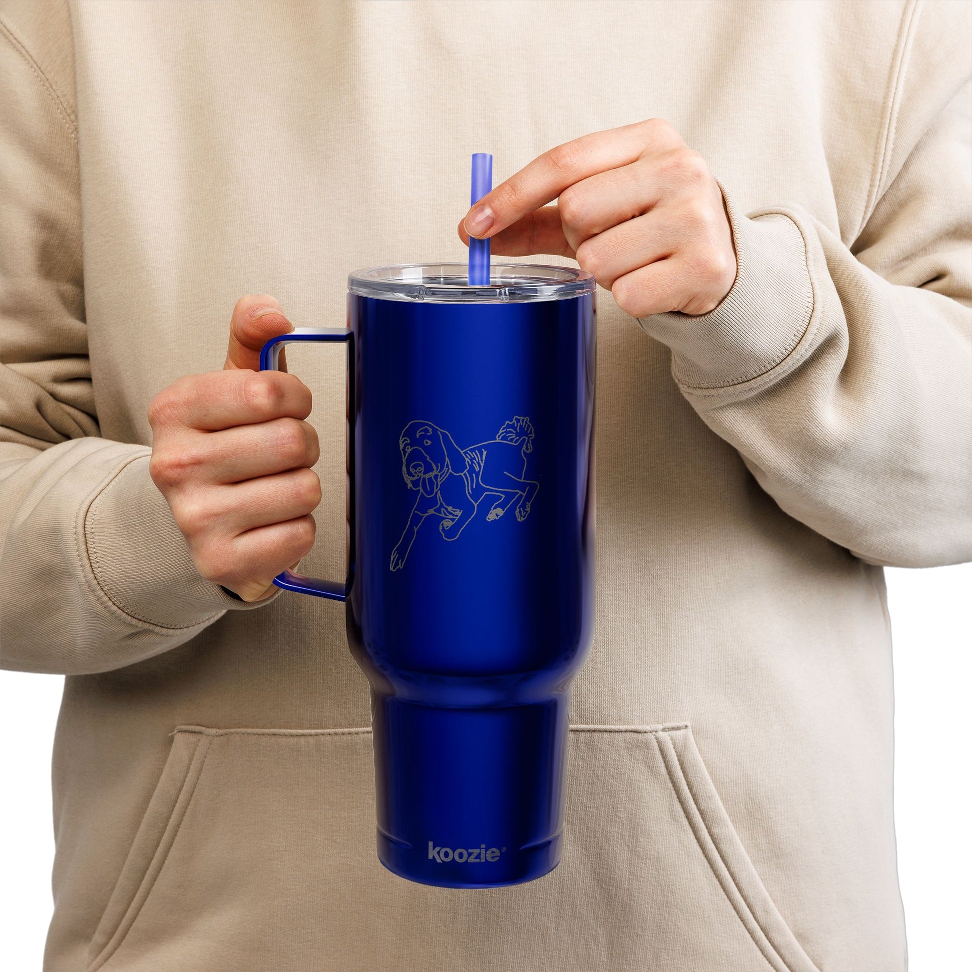 Person holding a blue insulated mug with a straw, wearing a beige hoodie.