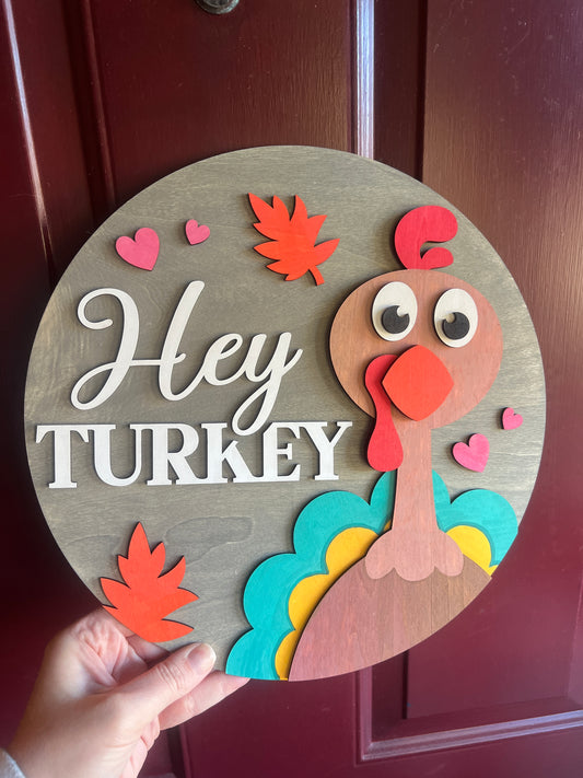 Decorative sign with a turkey design and 'Hey Turkey' text on a wooden background.