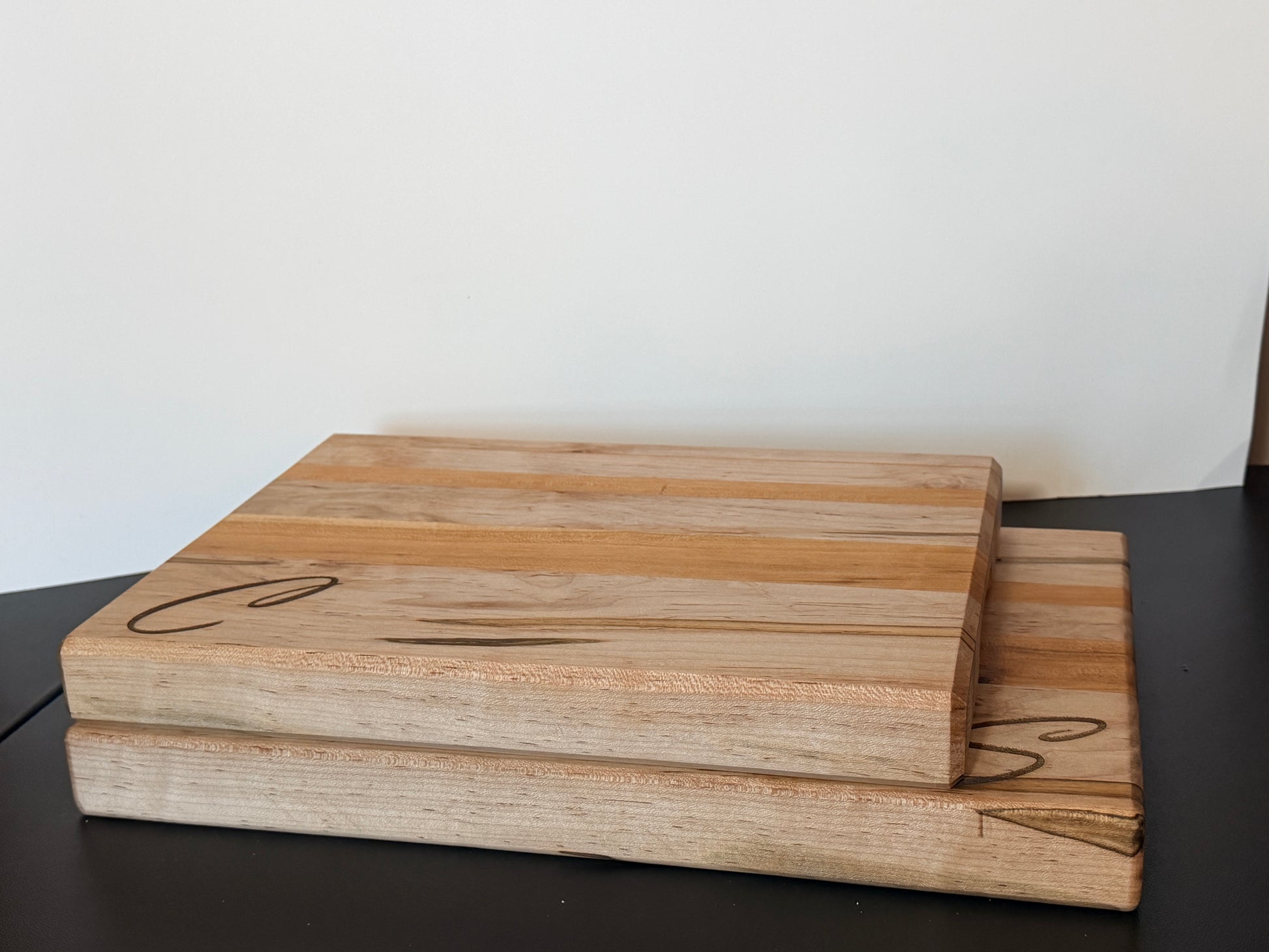 Handcrafted ambrosia maple and cherry wood cutting board with natural grain patterns and engraved initial, edge grain design with smooth finish