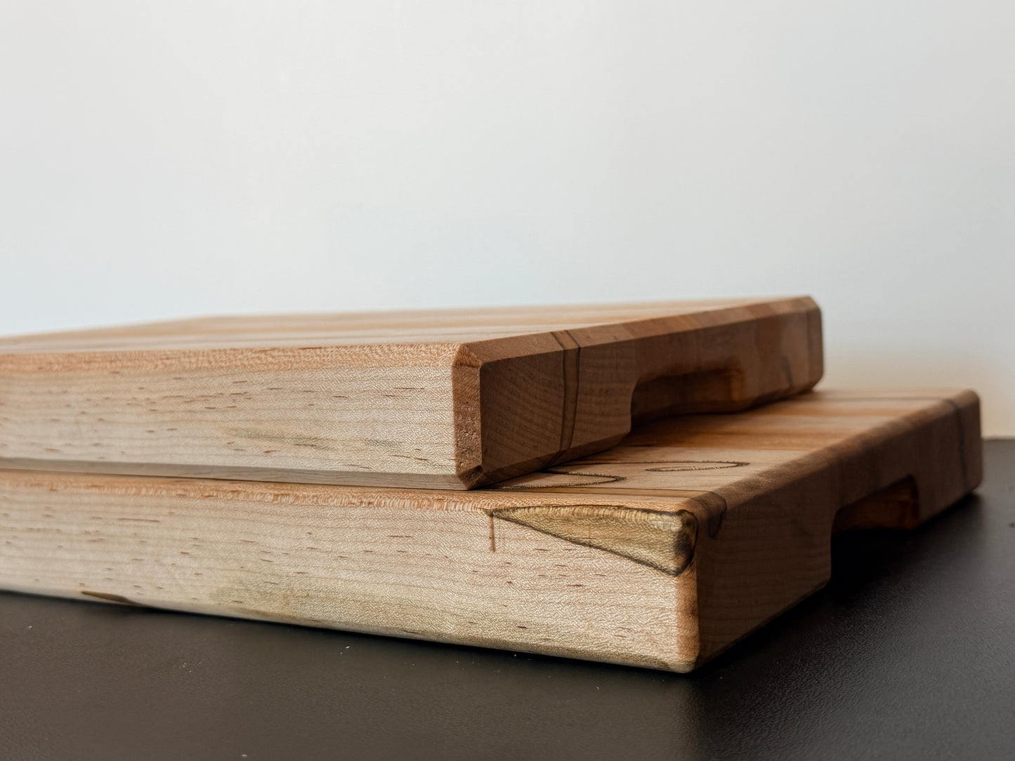 Side view of ambrosia maple and cherry cutting board showing edge grain construction and built-in side handles