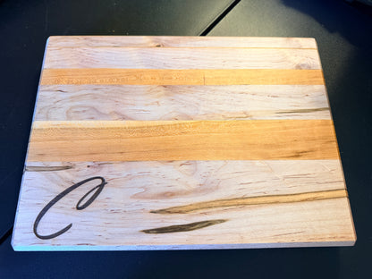 Handcrafted ambrosia maple and cherry wood cutting board with natural grain patterns and engraved initial, edge grain design with smooth finish