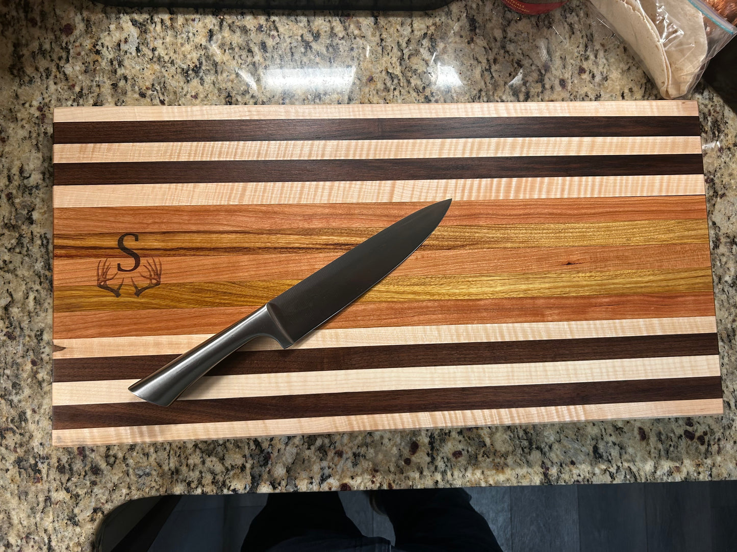 Wooden cutting board with knife on a granite countertop
