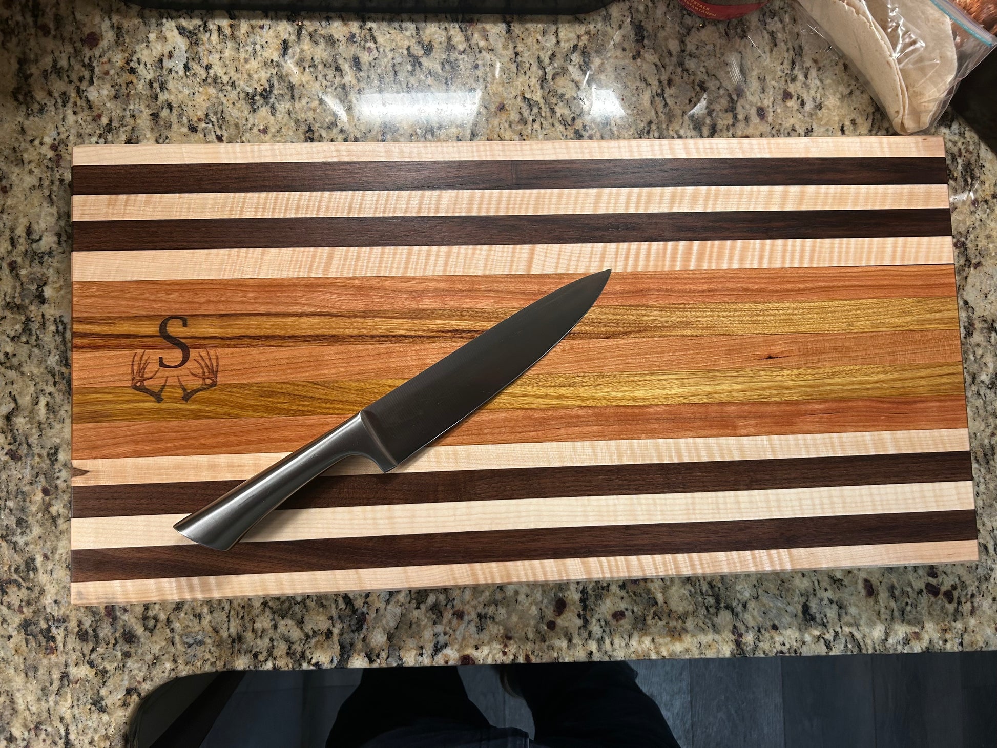 Wooden cutting board with knife on a granite countertop