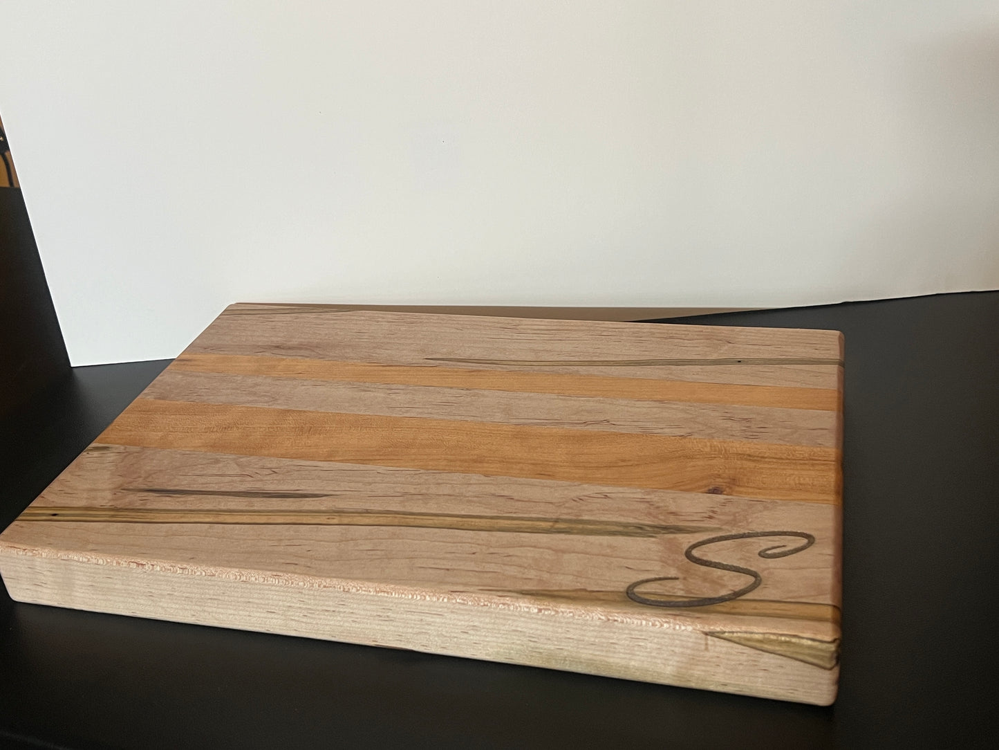 Handcrafted ambrosia maple and cherry wood cutting board with natural grain patterns and engraved initial, edge grain design with smooth finish