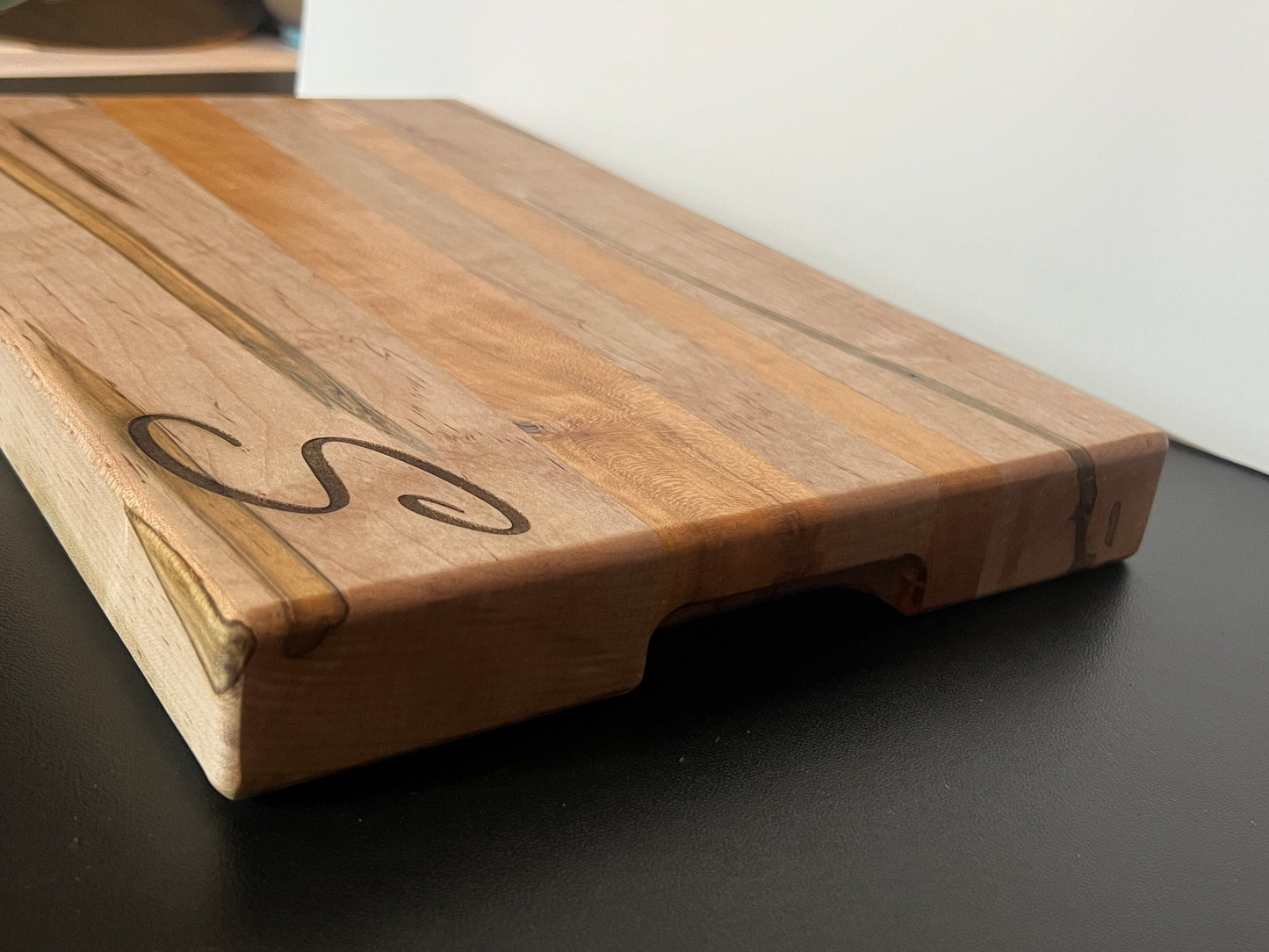 Side view of ambrosia maple and cherry cutting board showing edge grain construction and built-in side handles